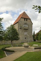 Schloss Sachsenhagen aus Bruchsteinen mit Erkerturm, umgeben von grünen Bäumen und gepflegter Anlage.