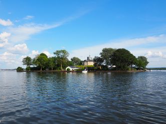 Insel Willemstein im Steinhuder Meer, umgeben von Wasser und Bäumen, mit einem markanten Gebäude.
